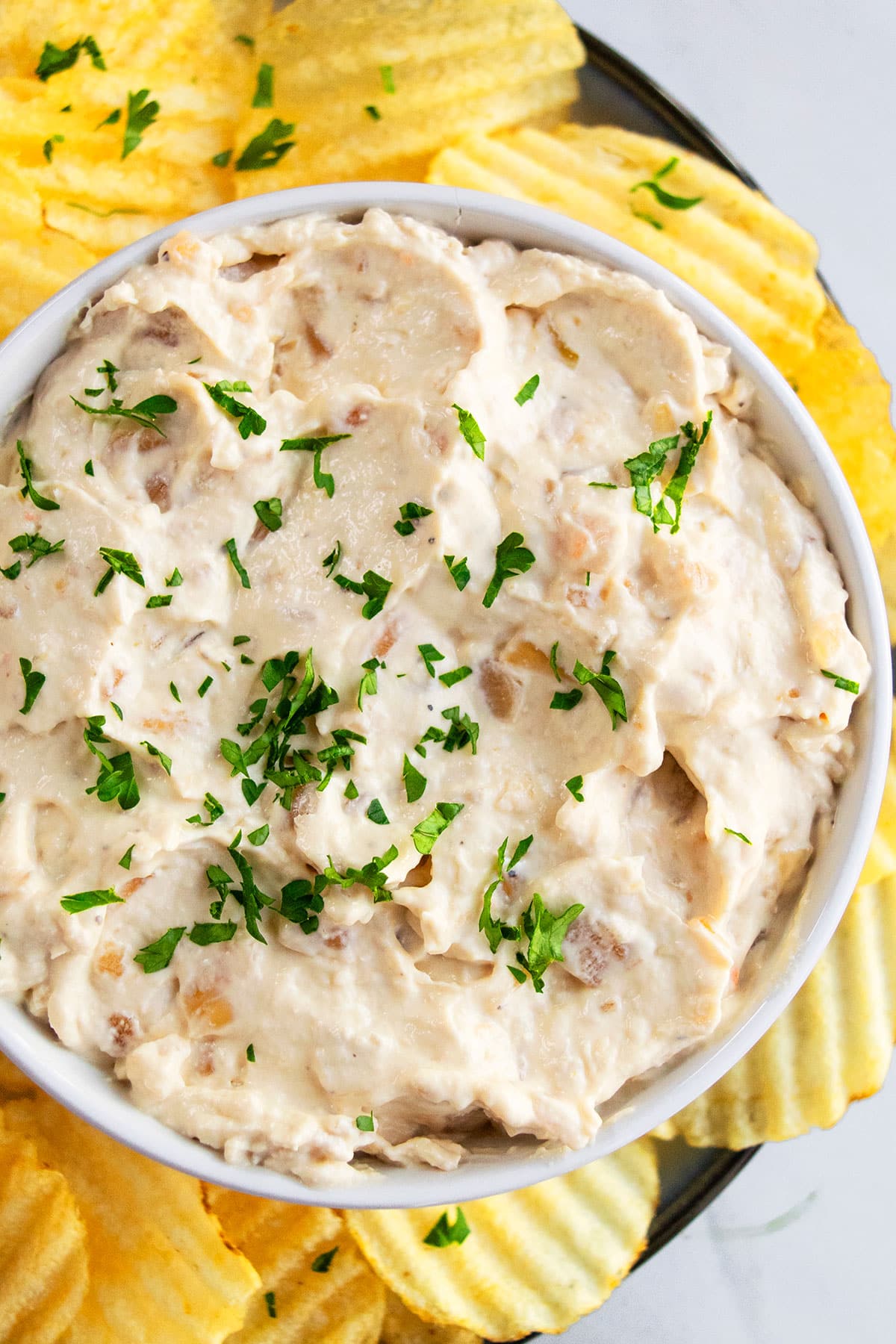 Sour Cream and Onion Dip in White Bowl With Parsley Garnish- Overhead Shot. 