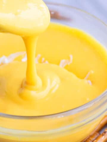 Spoonful of Homemade Cheese Sauce in a Glass Bowl.