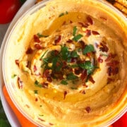 Bowl of Best Homemade Roasted Red Pepper Hummus For Dipping Carrots and Veggies.