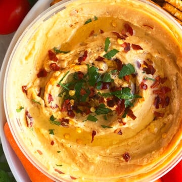 Bowl of Best Homemade Roasted Red Pepper Hummus For Dipping Carrots and Veggies.