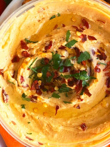Bowl of Best Homemade Roasted Red Pepper Hummus For Dipping Carrots and Veggies.