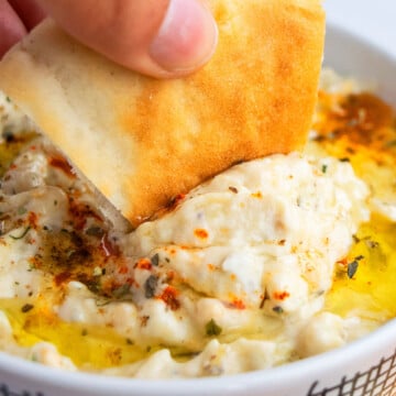 Pita Bread Being Dipped in Baba Ganoush Eggplant Dip in White Bowl- Closeup Shot.