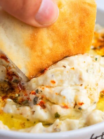 Pita Bread Being Dipped in Baba Ganoush Eggplant Dip in White Bowl- Closeup Shot.
