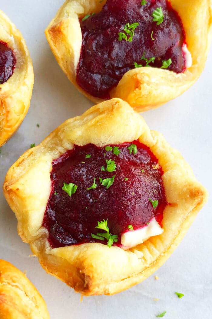 Baked Puff Pastry Cranberry Brie Bites on Marble Backdrop.