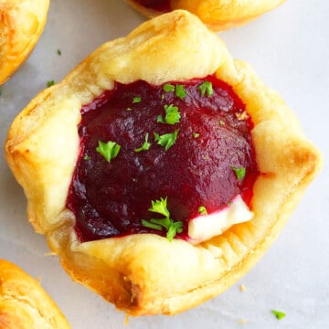 Easy Homemade Puff Pastry Cranberry Brie Bites Appetizer on White Marble Background- Closeup Shot.