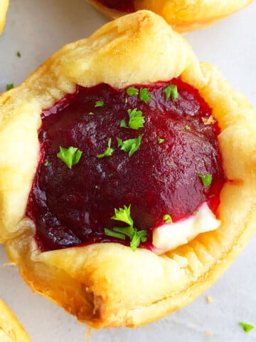 Easy Homemade Puff Pastry Cranberry Brie Bites Appetizer on White Marble Background- Closeup Shot.