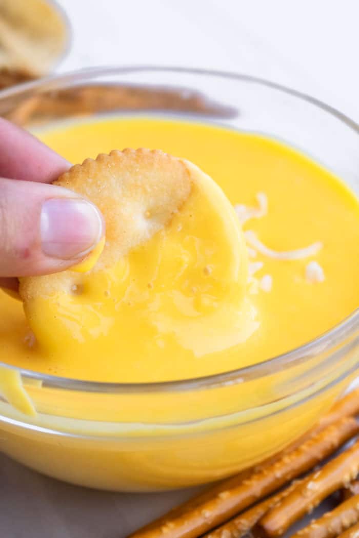 Cracker Being Dipped in a Bowl of Creamy Velveeta Cheese Sauce 