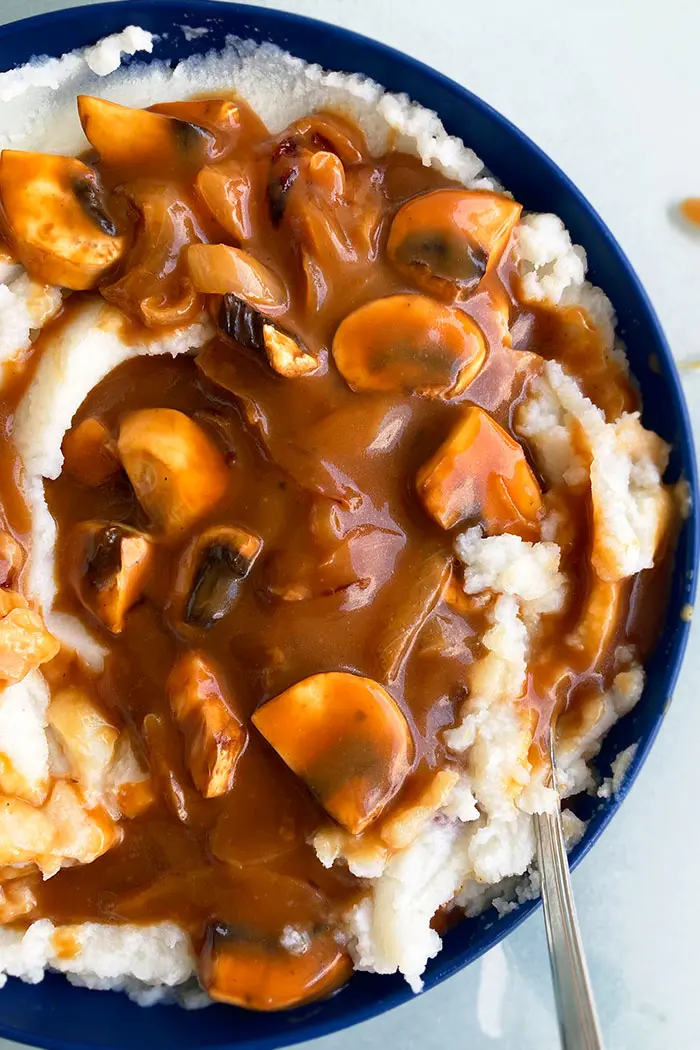 Homemade Mushroom Gravy Over Mashed Potatoes in Blue Bowl