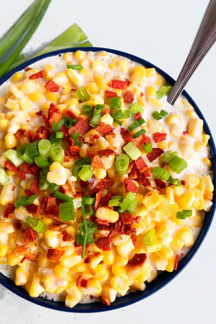 Best Homemade Creamed Corn in Dark Blue Bowl on White Background