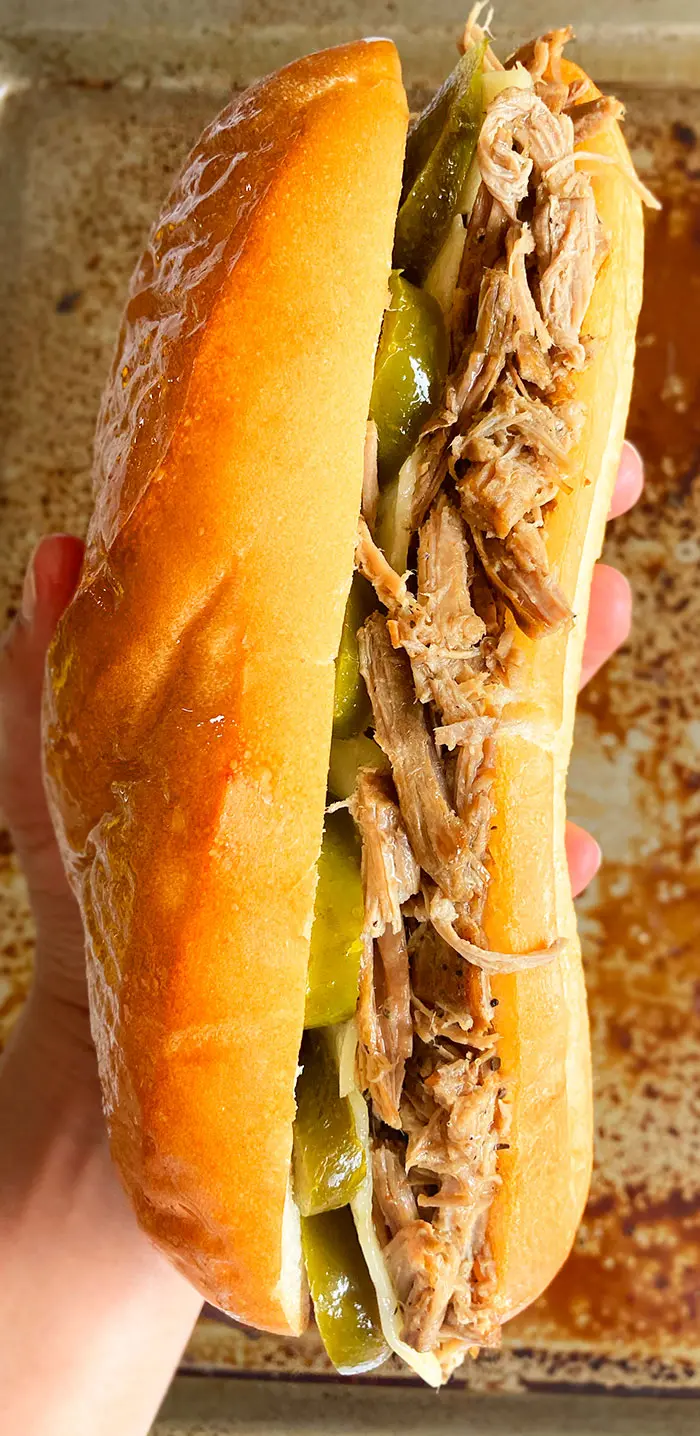 Closeup Shot of Holding a Homemade French Dip Sandwich in Hands on a Rustic Background