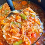 Closeup Shot of Spoonful of Homemade Cabbage Soup in Black Pot