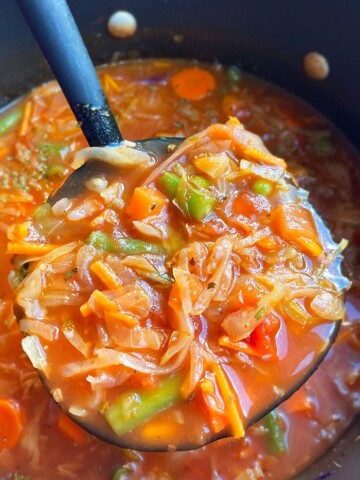 Closeup Shot of Spoonful of Homemade Cabbage Soup in Black Pot