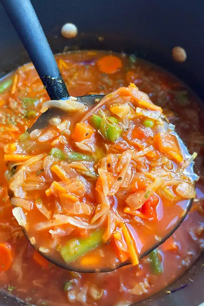 Closeup Shot of Spoonful of Homemade Cabbage Soup in Black Pot