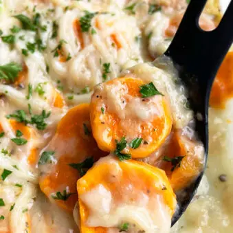 Easy Homemade Scalloped Sweet Potatoes with Cheese in Glass Baking Dish on White Surface