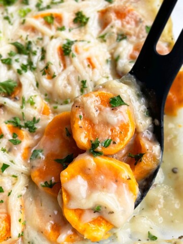 Easy Homemade Scalloped Sweet Potatoes with Cheese in Glass Baking Dish on White Surface