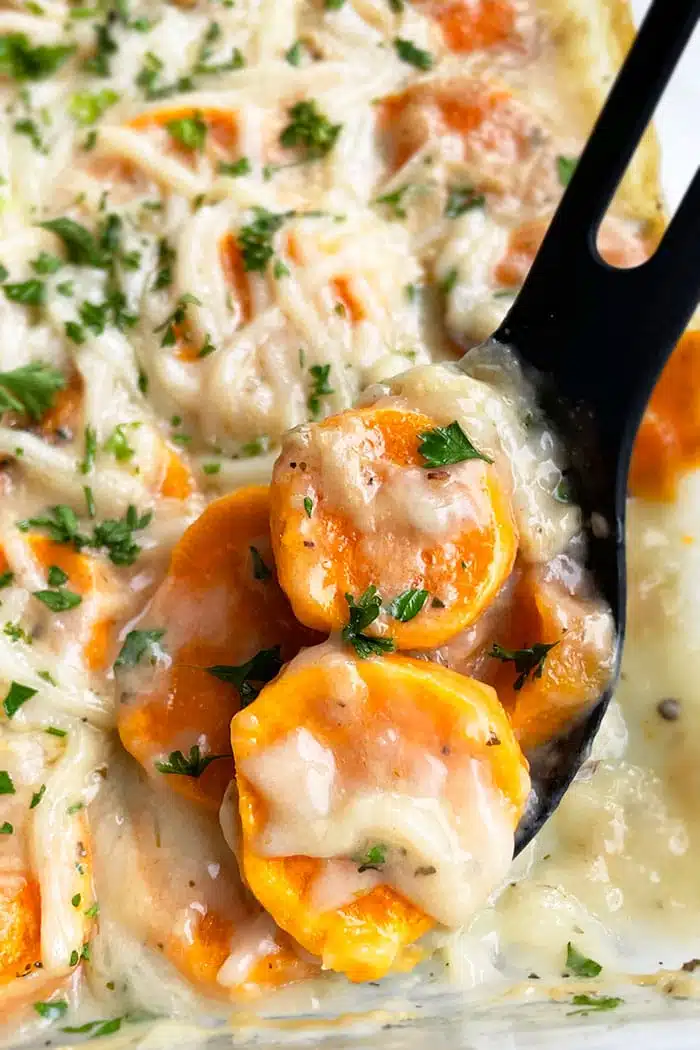 Spoonful of Easy Scalloped Sweet Potatoes with Cheese Mixture in Glass Dish- Closeup Shot