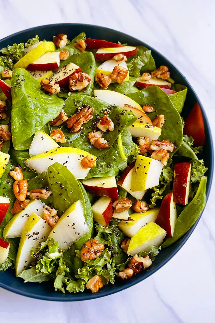 Overhead Shot of Easy Thanksgiving Salad with Apple Cider Vinaigrette in Blue Bowl on White Background