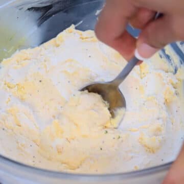 Cheese mixture being scooped with a spoon. 
