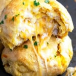 Stack of Two Stuffed Cheese Bombs on Black Baking Tray With Cheese Melting Out