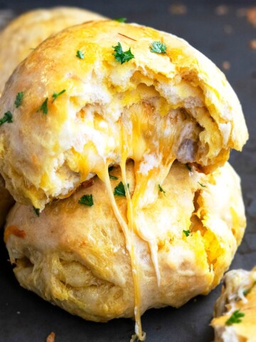 Stack of Two Stuffed Cheese Bombs on Black Baking Tray With Cheese Melting Out