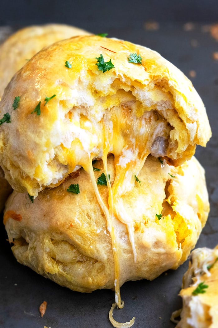 Stack of Two Stuffed Cheese Bombs on Black Baking Tray With Cheese Melting Out