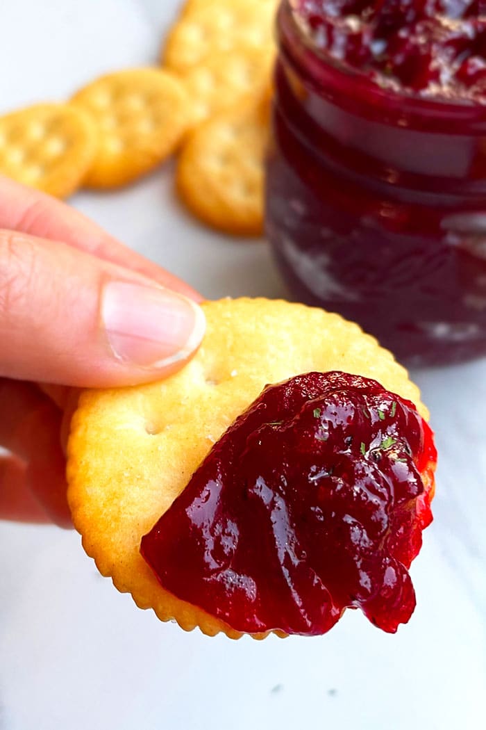 Fingers Holding Ritz Cracker That's Spread with Christmas Chutney