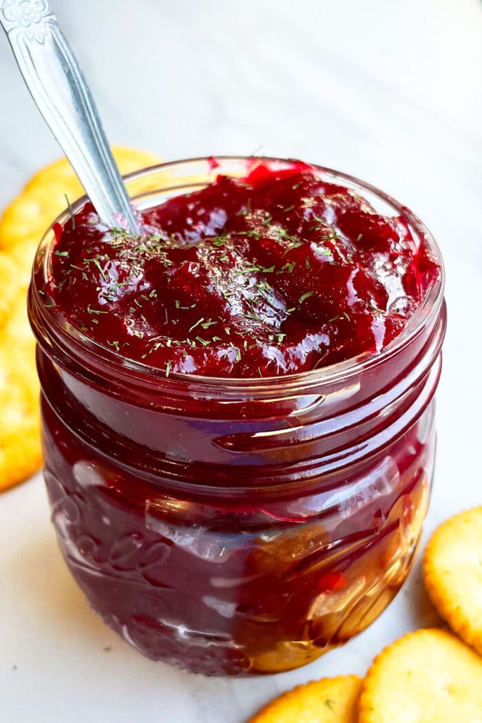 Easy Homemade Cranberry Chutney In Glass Jar on White Marble Background.