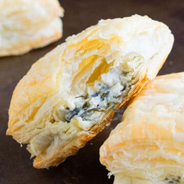 Easy One Pan Savory Cheese and Spinach Puffs With Partial Bite Removed on Black Tray.