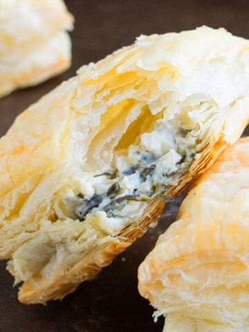 Easy One Pan Savory Cheese and Spinach Puffs With Partial Bite Removed on Black Tray.