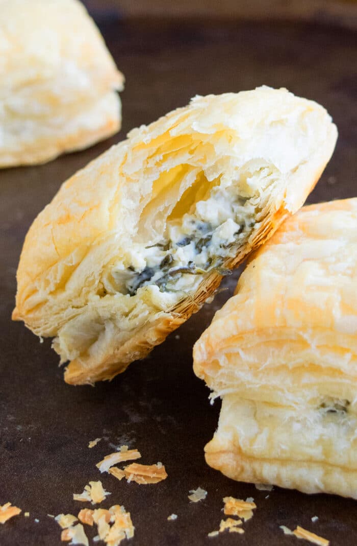 Partially Eaten Spinach Puffs with Cheese and Italian Herbs, Placed on Rustic Black Tray.