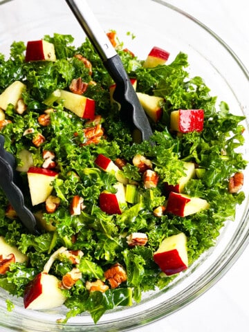 Easy Massaged Kale Salad in Glass Bowl With Tongs- Overhead Shot