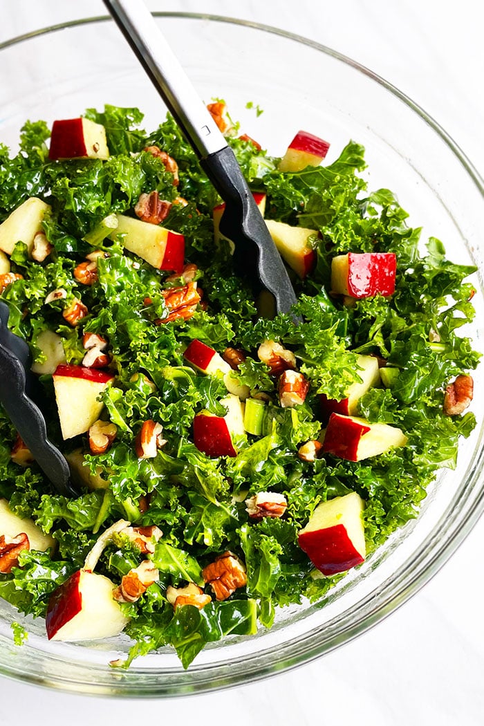 Easy Kale Apple Salad in Glass Bowl With Tongs- Overhead Shot