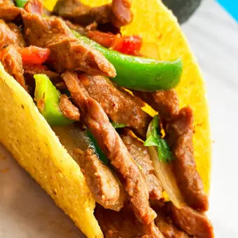 Instant Pot Flank Steak Tacos in Hard Tortilla Shell on White Background