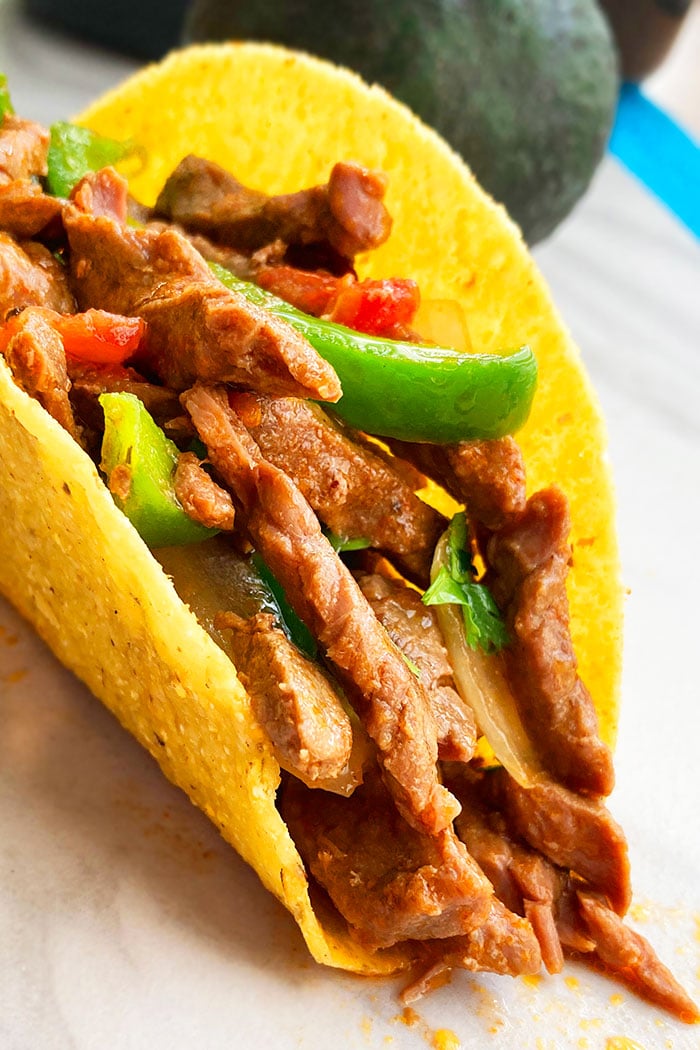 Instant Pot Flank Steak Tacos in Hard Tortilla Shell on White Background