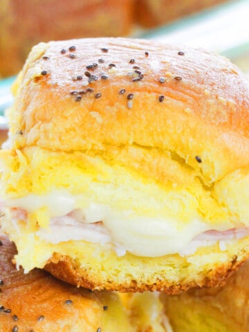 Closeup Shot of Easy Ham and Cheese Sliders With Garlic Butter Stacked on One Another in a Plate.