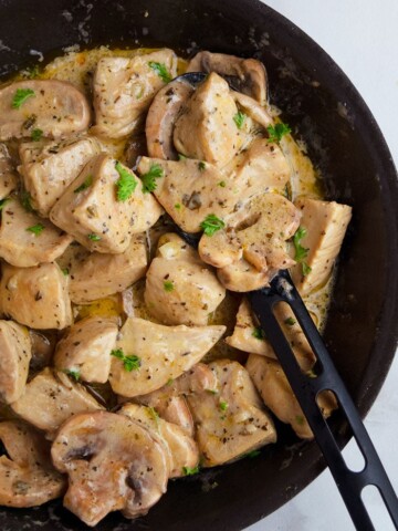 Easy Instant Pot Cream of Mushroom Chicken in Black Dish With Black Spoon on White Background