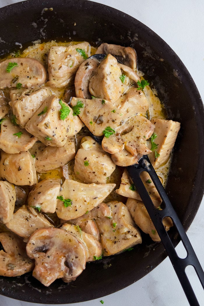 Easy Instant Pot Cream of Mushroom Chicken in Black Dish With Black Spoon on White Background