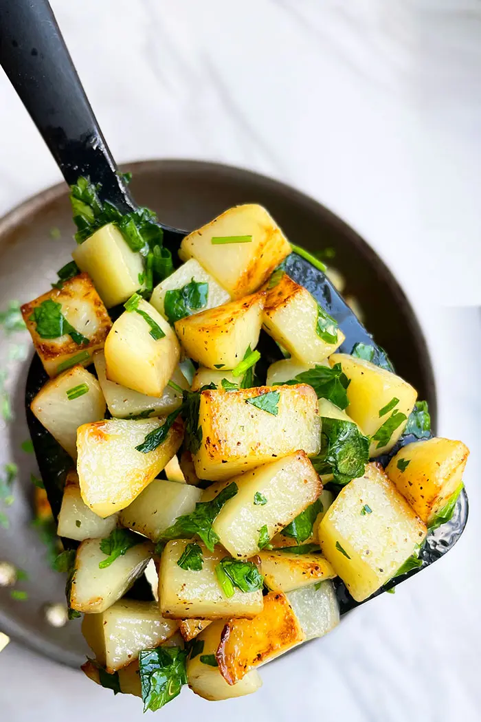 Spoonful of Herbed Potatoes over White Background- Closeup Shot