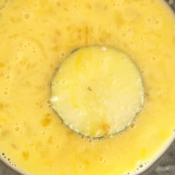 Floured zucchini being dipped in egg mixture.