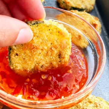 Courgette chip being dipped in red sauce.