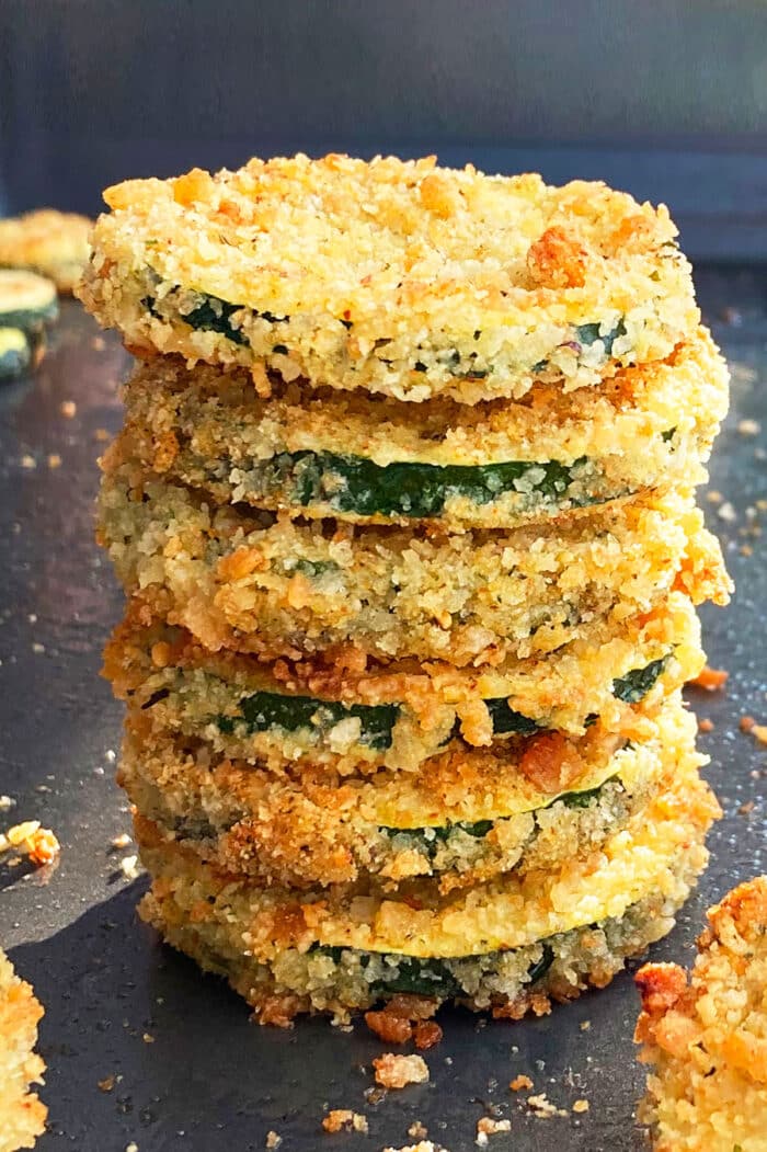 Stack of crispy zucchini chips on baking tray.