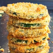 Stack of oven baked crispy zucchini chips or courgette chips on an unlined tray.