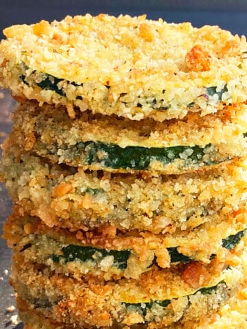 Stack of oven baked crispy zucchini chips or courgette chips on an unlined tray.