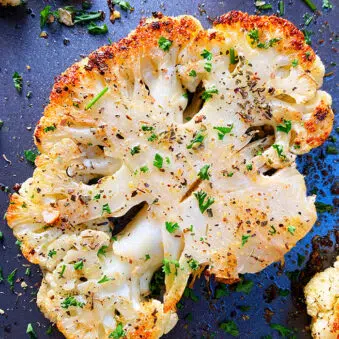 Crispy Roasted Cauliflower Steak With Italian Herbs on Dark Baking Tray