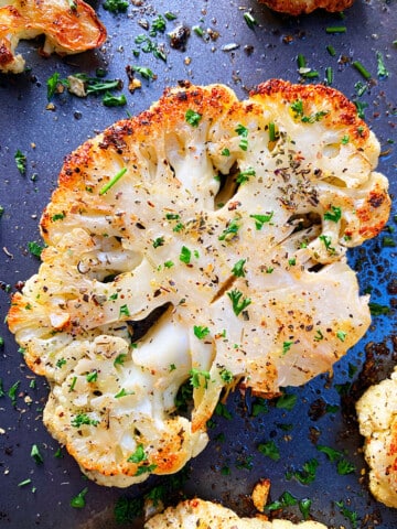 Crispy Roasted Cauliflower Steak With Italian Herbs on Dark Baking Tray