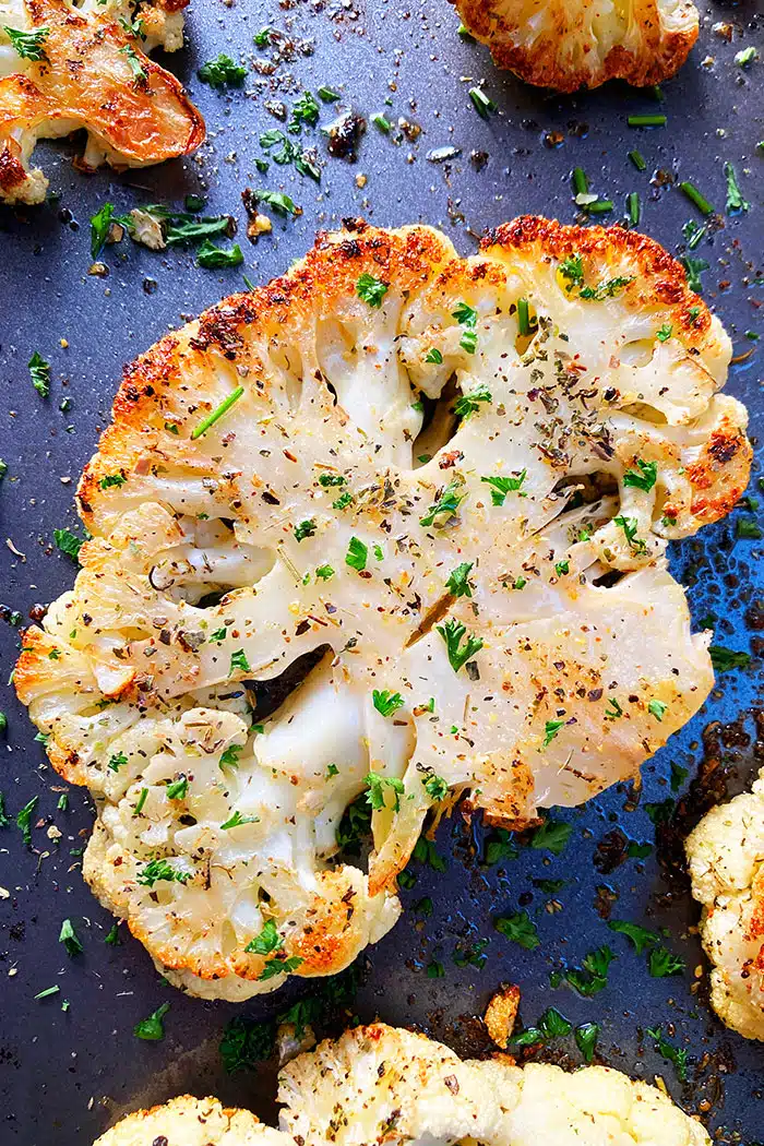 Crispy Roasted Cauliflower Steak With Italian Herbs on Dark Baking Tray