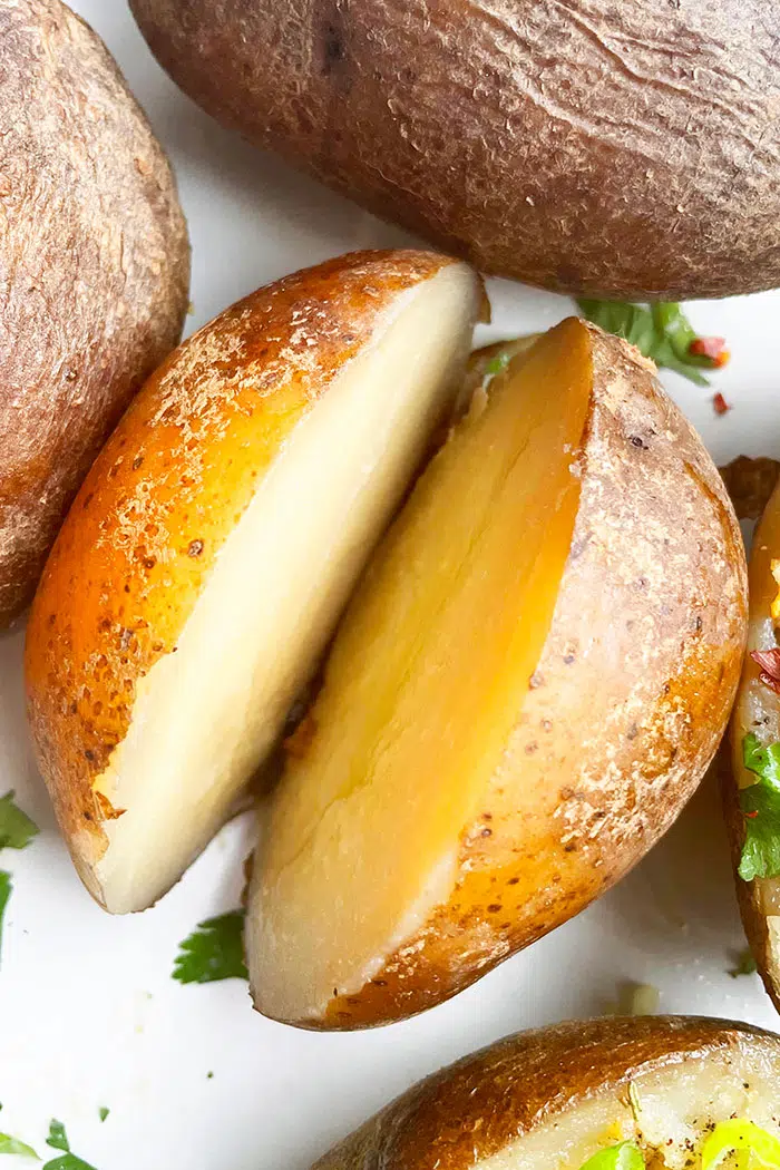 Easy Microwave Baked Potatoes Sliced in Half With No Toppings, on White Plate