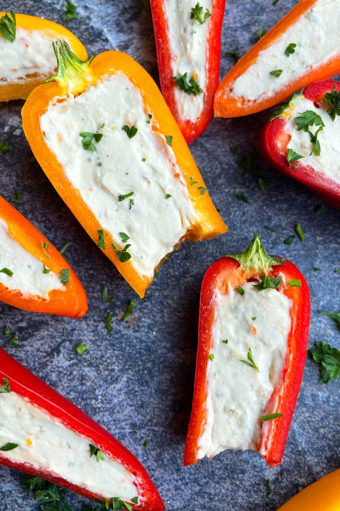 Partially eaten cheese filled bell peppers on rustic gray background.