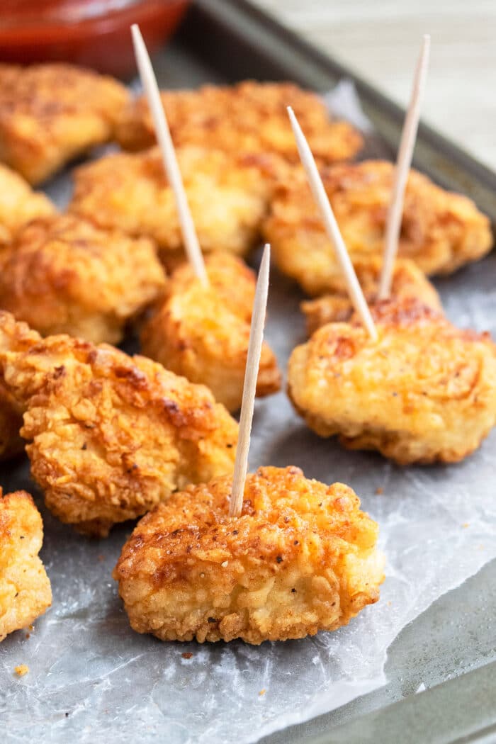 Crispy mini breaded chicken with cornflakes coating with toothpicks attached to them.