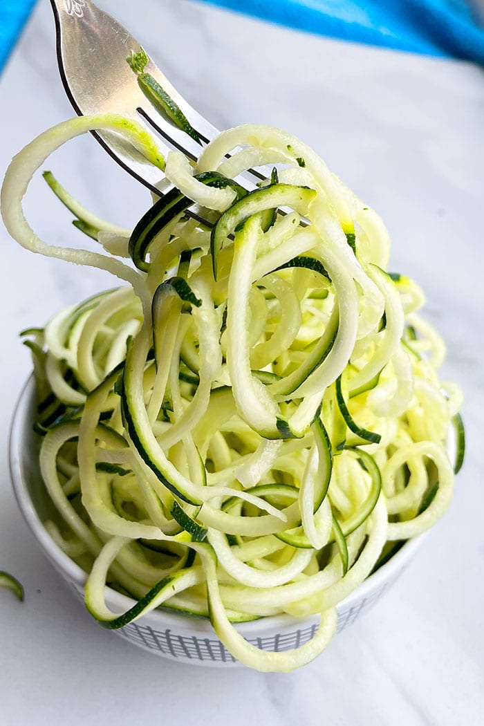 Fork Full of Homemade Zoodles Over White Bowl